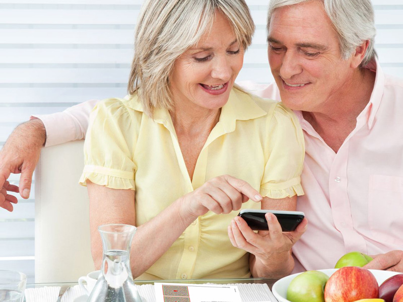 Elderly smiling couple listens to package insert via their smartphone - for more customer satisfaction