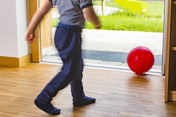 Accessible solutions - inclusion: boy with a ball uses threshold-free exit to garden