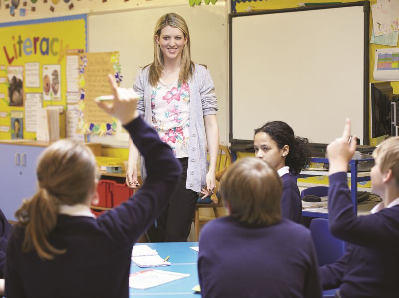 Young female teacher with pupils in the class room overcoming reading difficulties