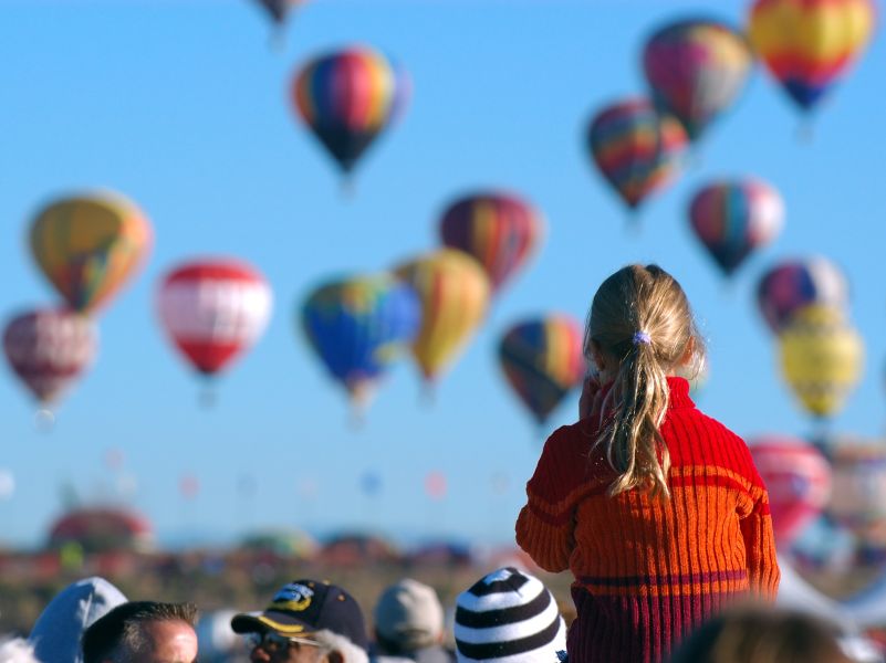 Zuschauer von hinten, die viele Heißluftballons am Himmel beobachten